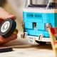 A photo of a Lego tire being fitted to a model VW bus.